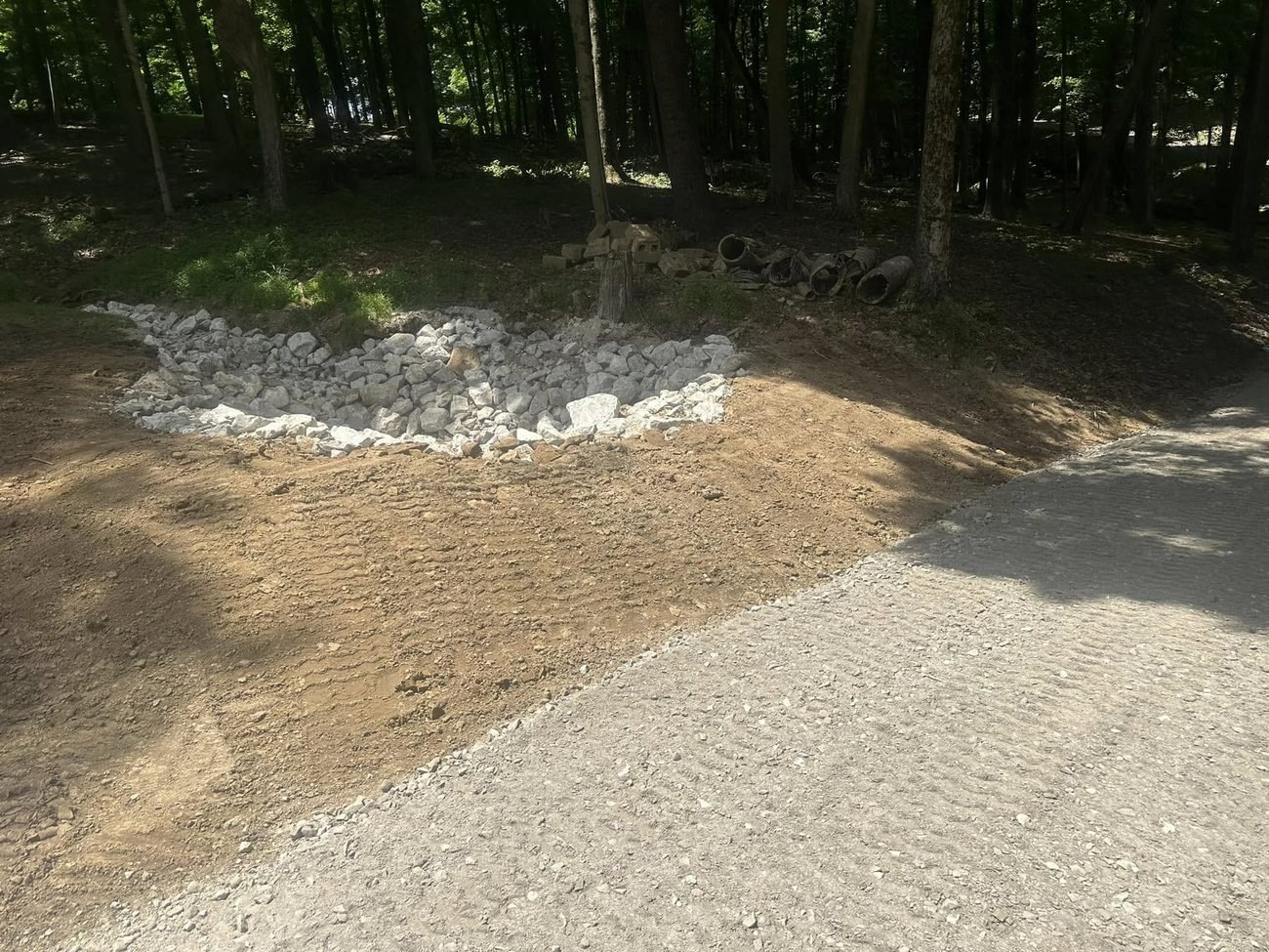 The same low spot rebuilt as a rip-rap lined basin at the edge of a graded gravel drive